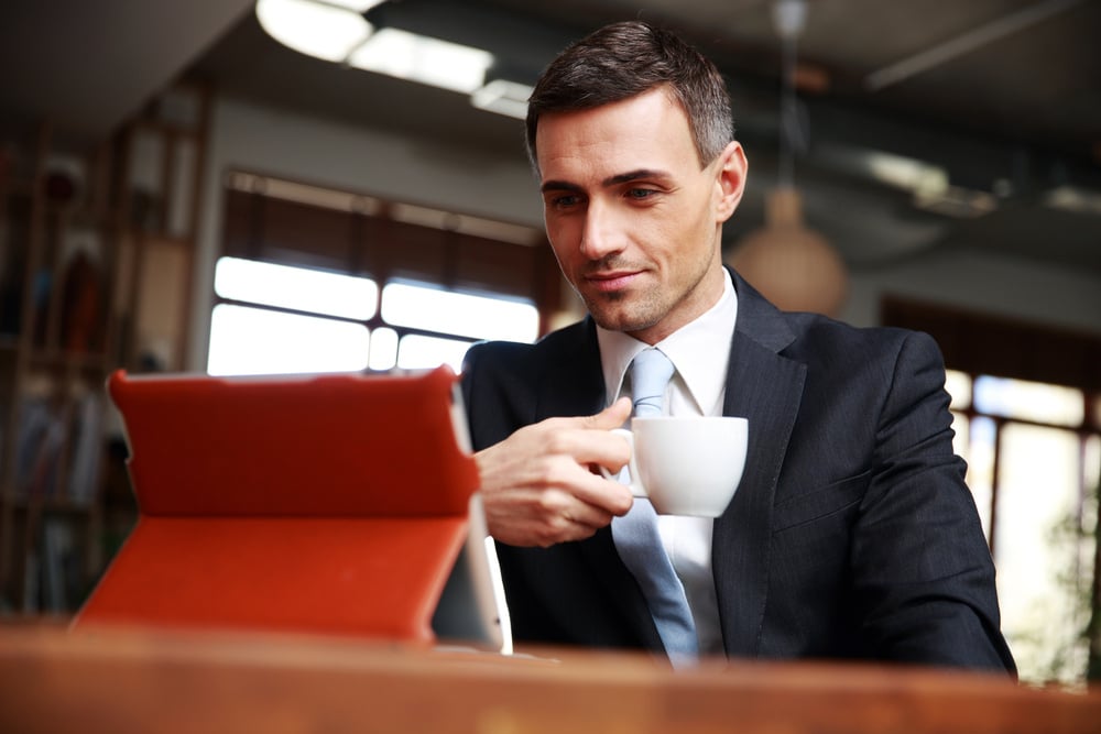 male business owner reading news on tablet, seven benefits of low interest rates