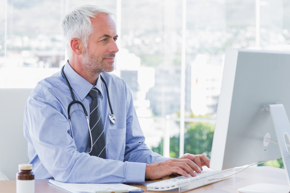 male doctor typing on his computer, healthcare practice loans