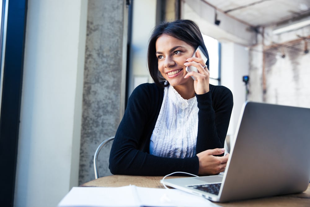 smiling business owner on phone at desk, business tax changes for 2025