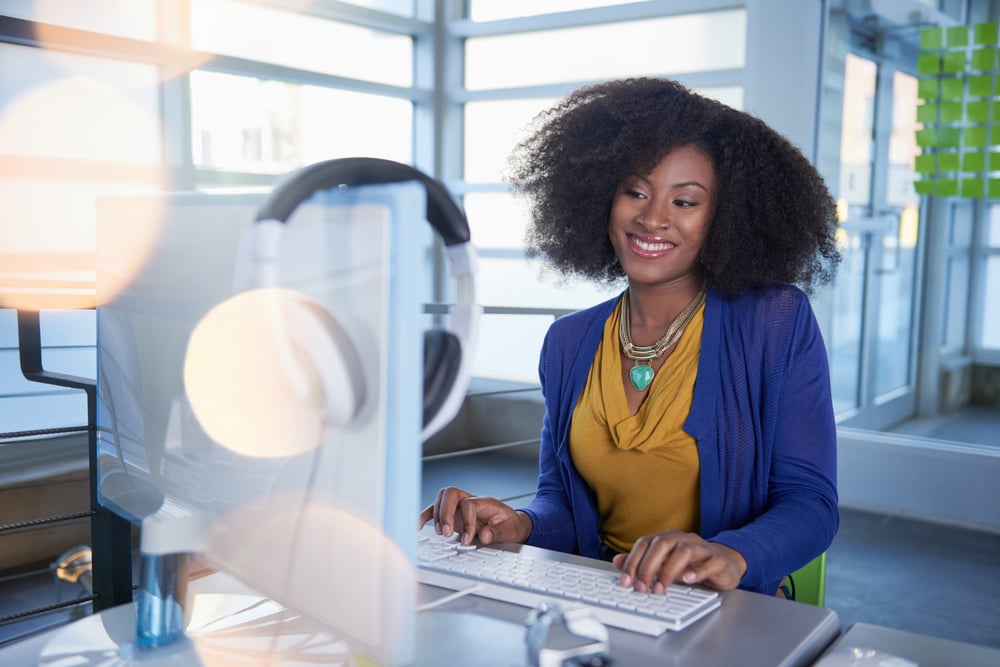 portrait of a smiling business woman at the computer in bright glass office, working capital loan calculator