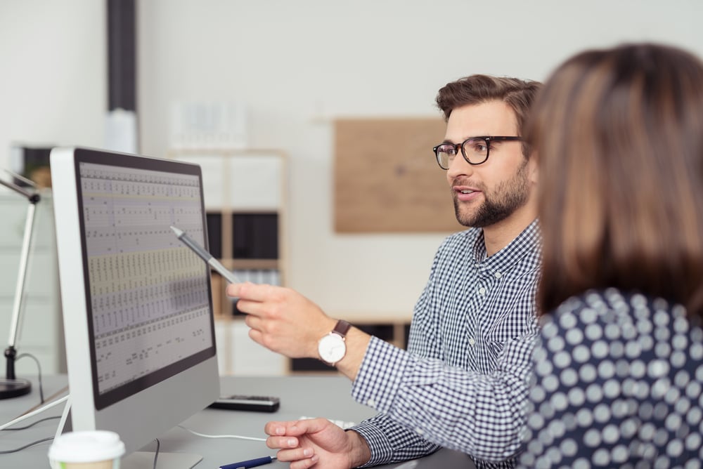 proficient young male business owner with eyeglasses and checkered shirt talking to an employee