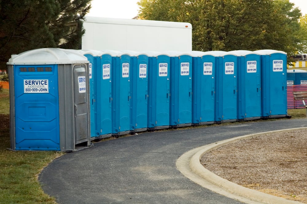 row of porta potty units at a job site, blue portable restrooms at a construction site, portable sanitation business tips