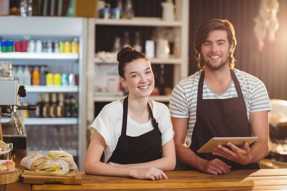 two cafe business owners smiling at counter of cafe, end-of-year tax tips for businesses