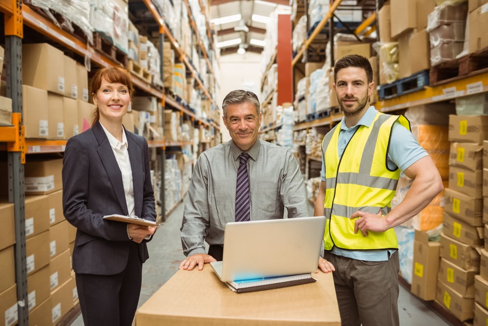 smiling warehouse team working together on laptop in a large warehouse, equipment vendor financing