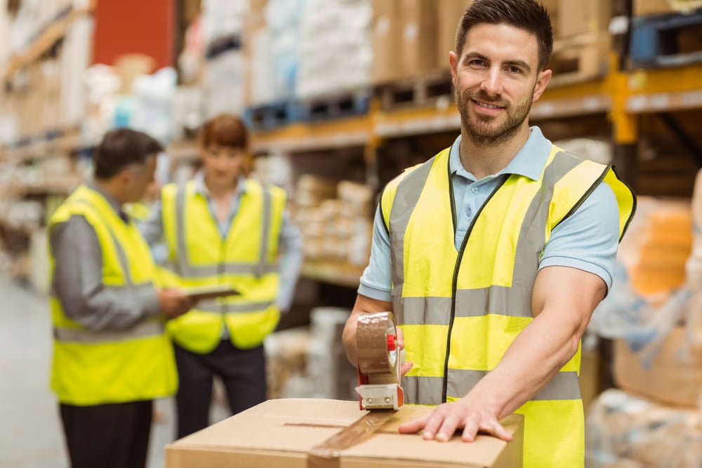 smiling warehouse workers preparing a shipment in a large warehouse