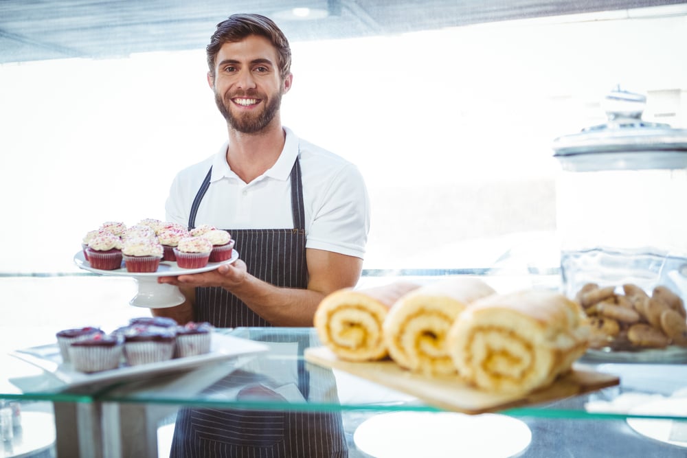 smiling bakery owner holding cupcake tray, how to handle slow seasons
