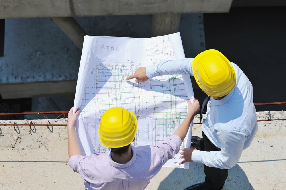 two architects looking at construction plans at a job site