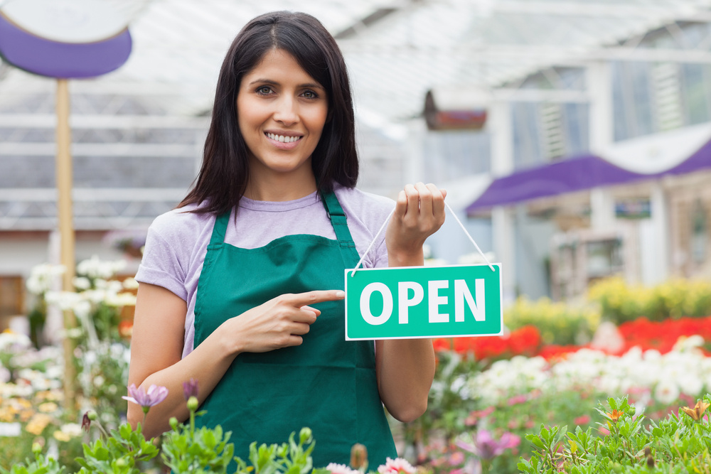 female gardening store owner holding open sign, retail business loans
