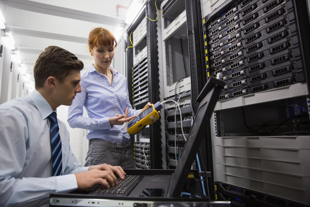 team of technicians using digital cable equipment on servers in large data center