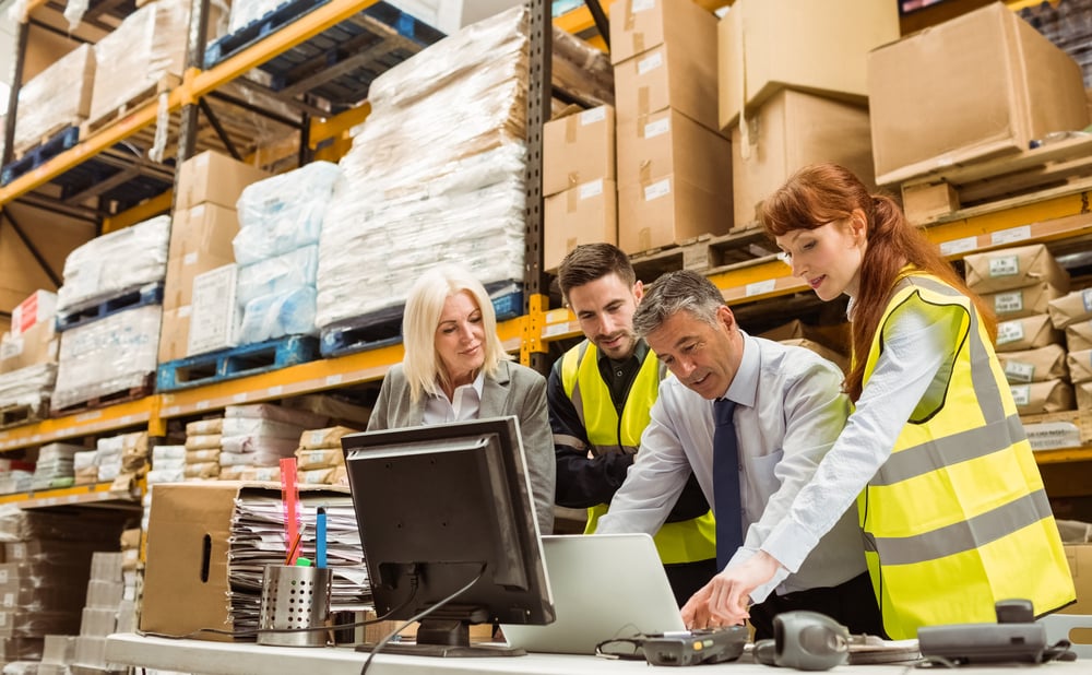 warehouse workers discussing business near a laptop computer, guide to equipment leasing